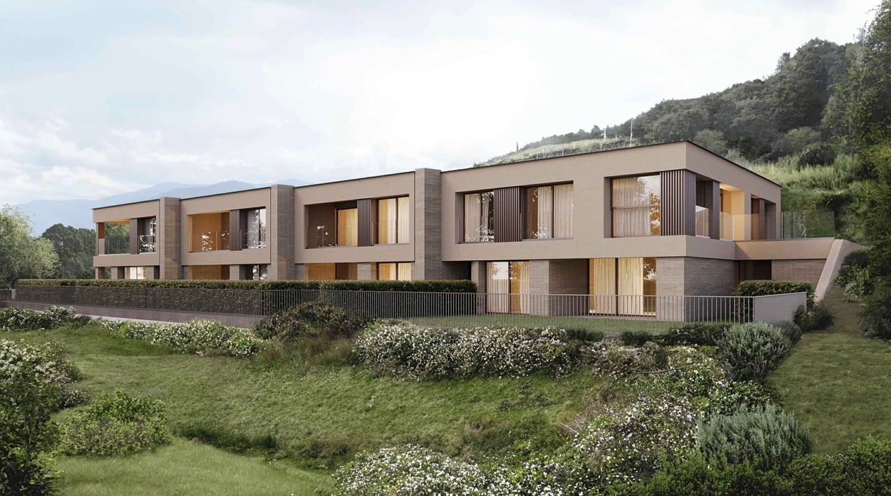 Modern architectural design, multiple windows, elevated ground floor, surrounded by a grassy area with a garden and a fence