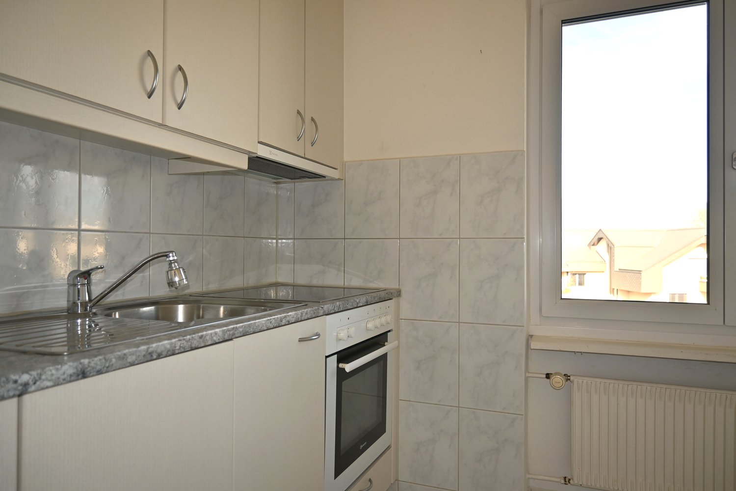 white cabinets, white tiled walls, stainless steel sink with faucet, white oven