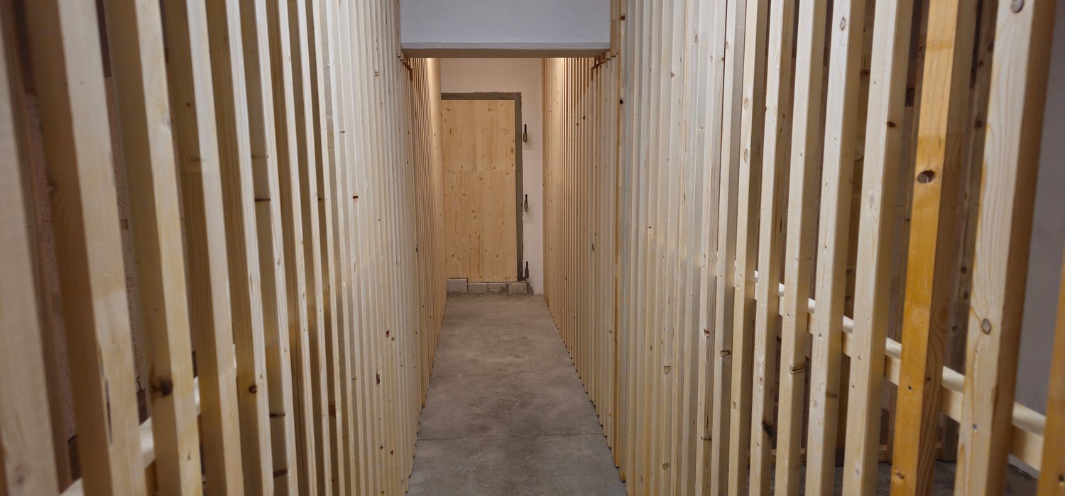 Wooden walls, cement floor, a door in the middle