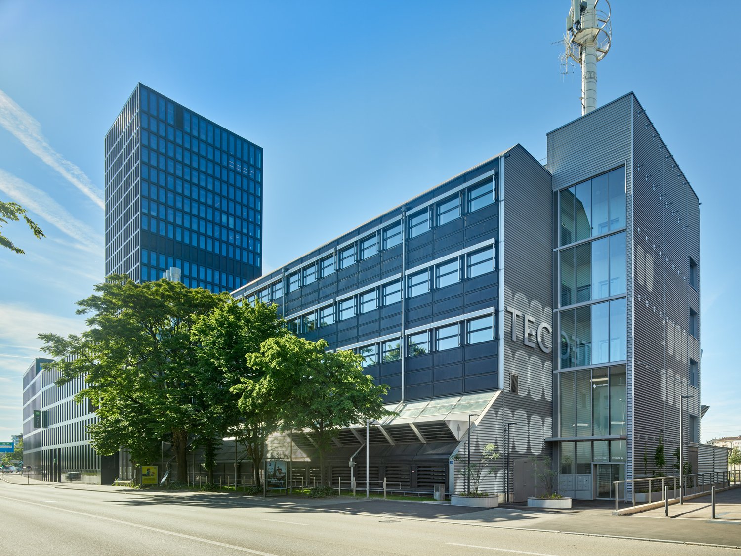 Modern office building with glass facades, multiple floors, and a tower on top