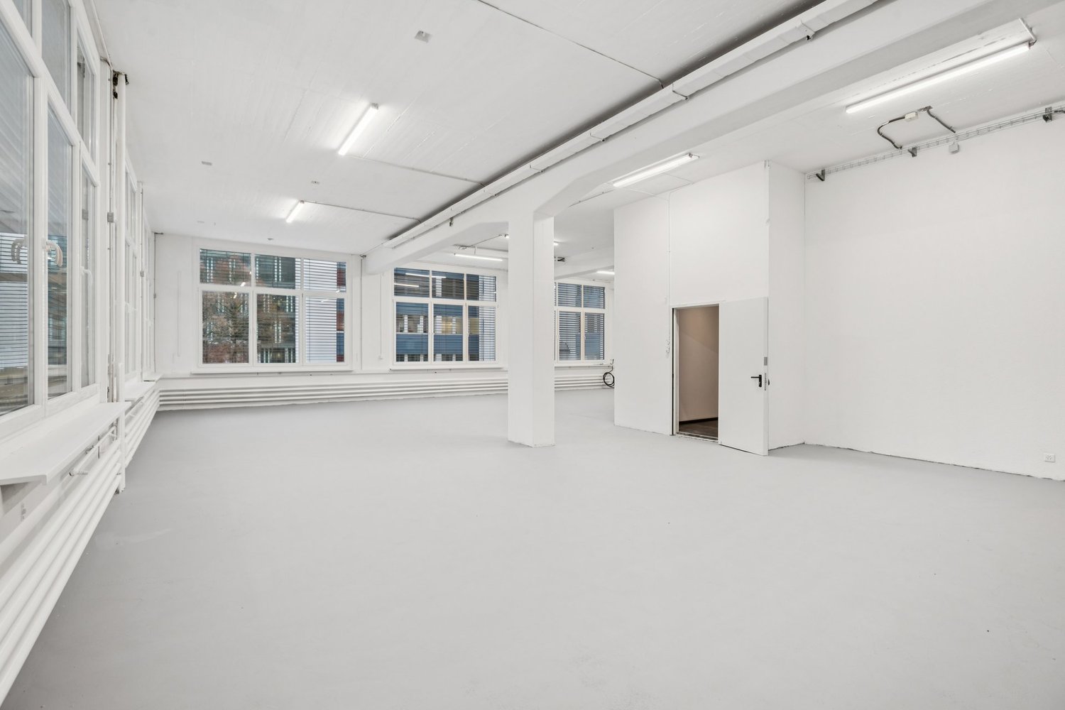 Empty room with white walls, white floor, large windows, white ceiling, white door, white pillars