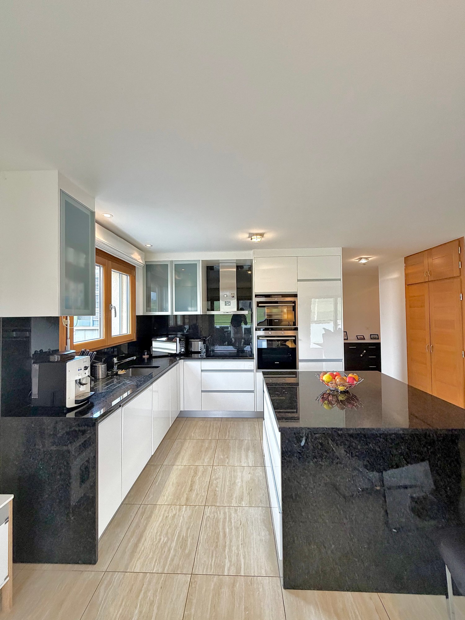 modern kitchen, black granite countertop, white cabinets, tiled floor, ceiling lights, white ceiling