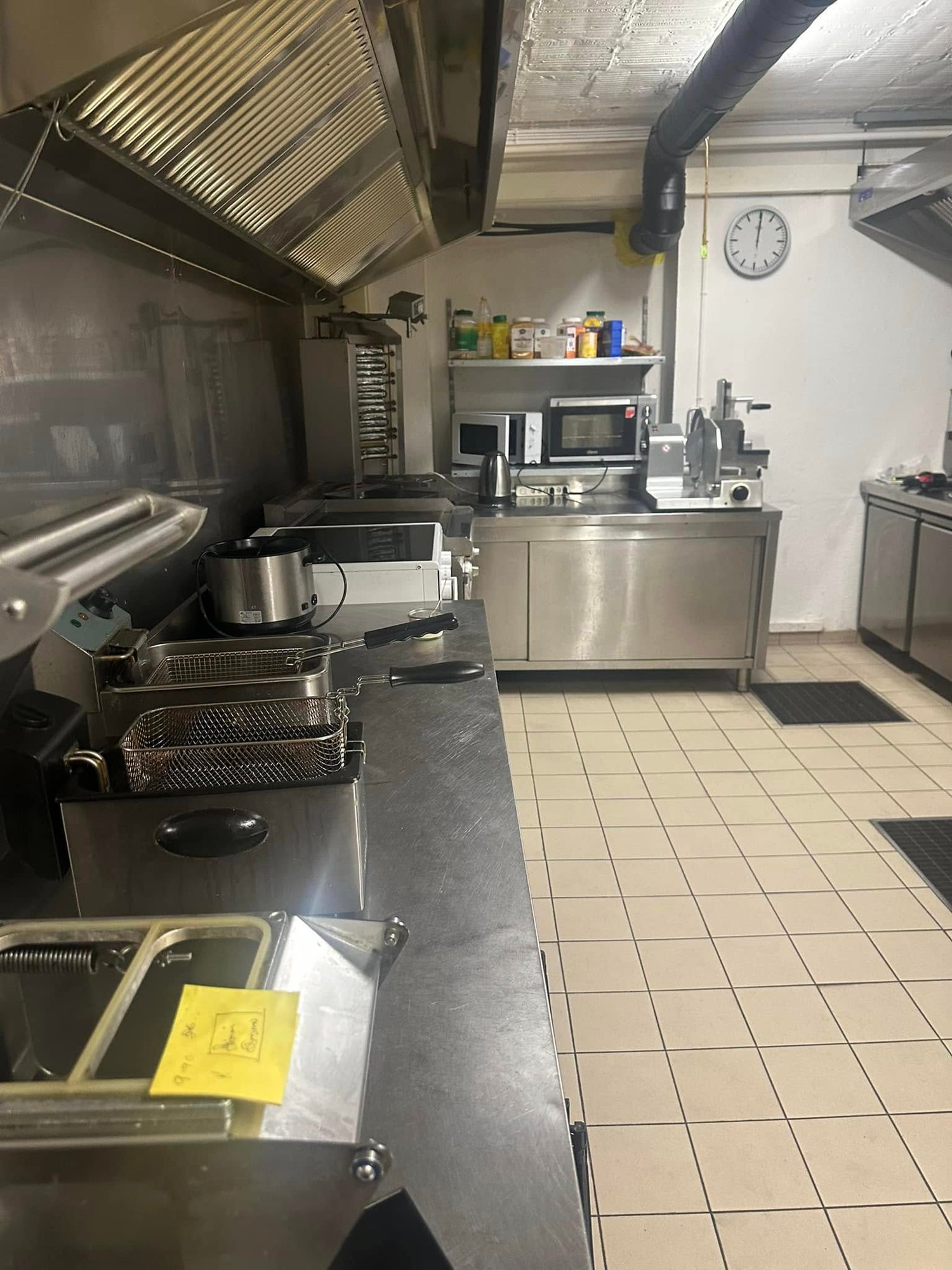 commercial kitchen with oven, microwave, deep fryers, and counter tops, tile flooring