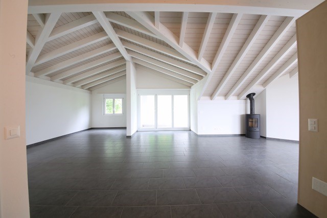 empty room with wooden beam ceiling, gray floor, fireplace