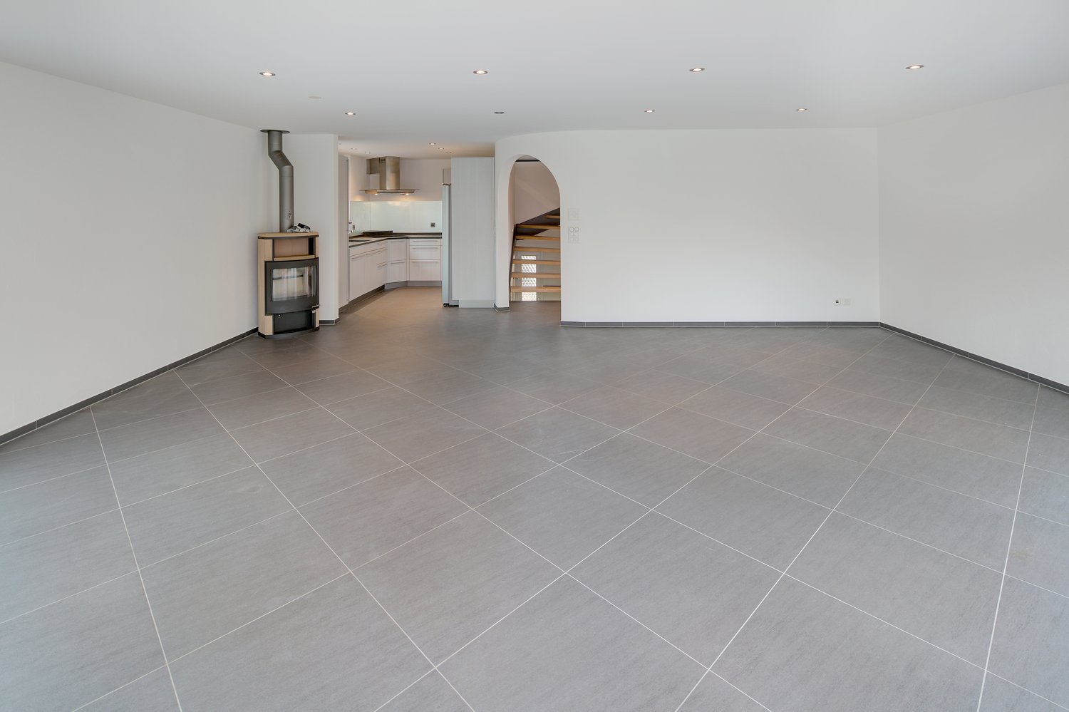 empty room, fireplace, tiled floor, kitchen area visible