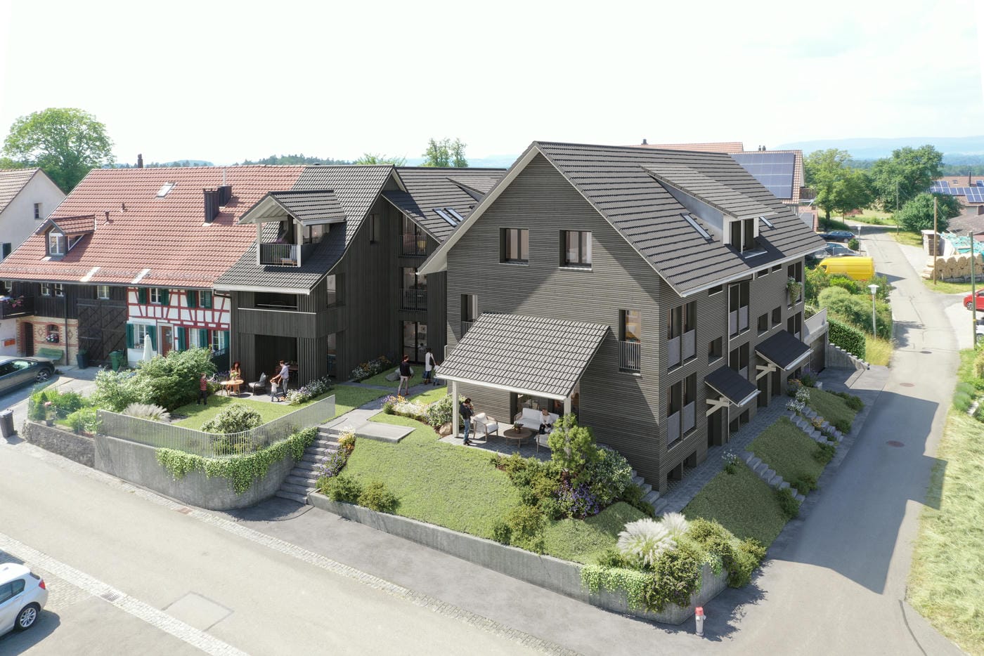 Multi-story apartment building with black wooden siding, slanted roofs, balconies, and a landscaped courtyard with parking spaces