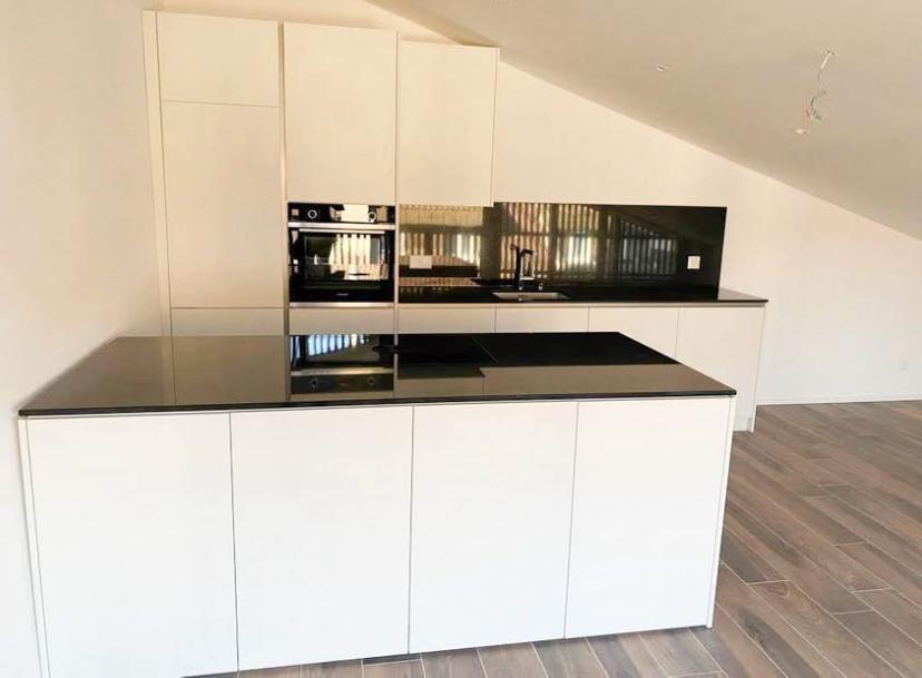 white kitchen, black countertops, integrated appliances, wooden flooring