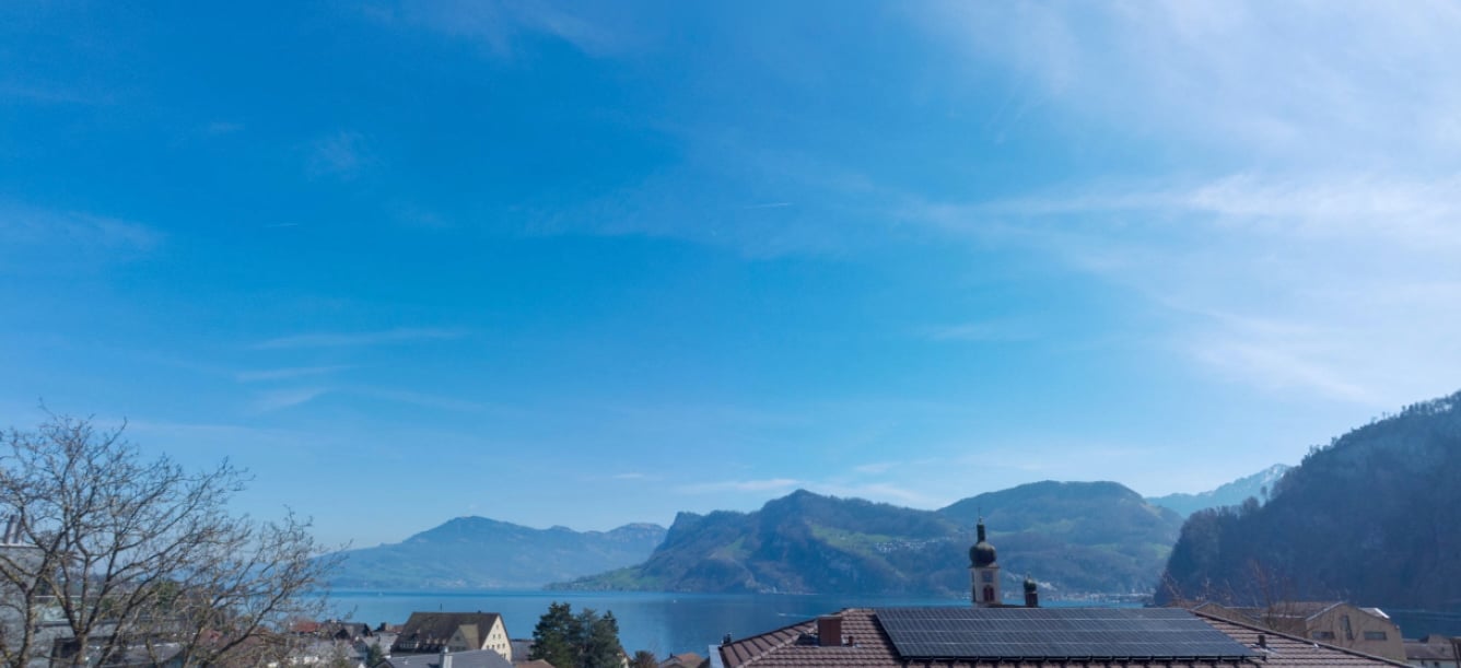 House with solar panels on the roof, overlooking a lake and mountains