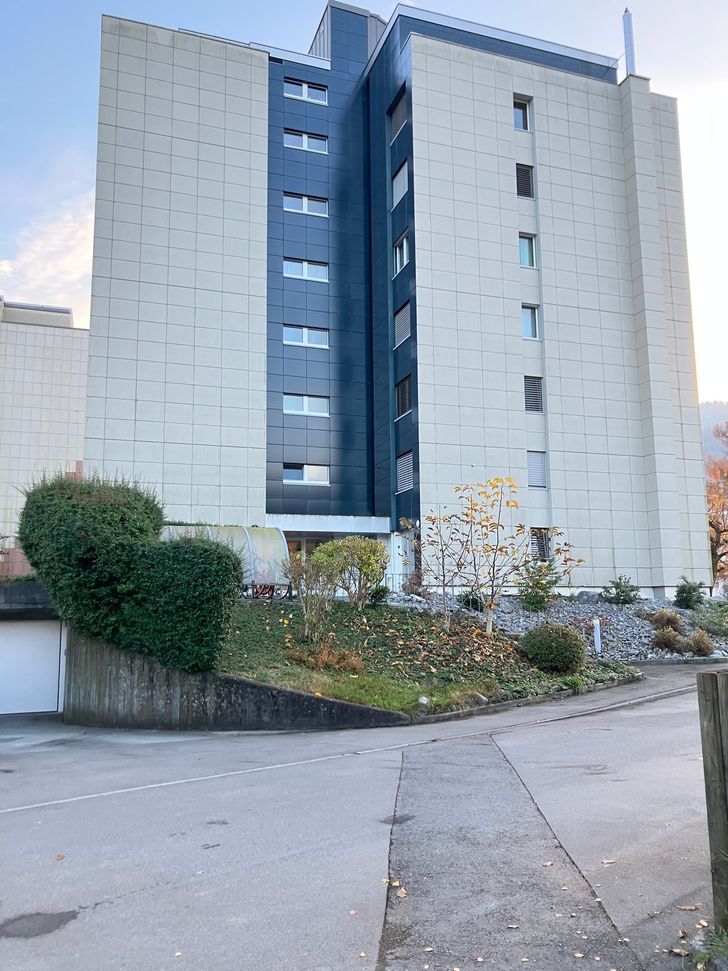 modern apartment building with multiple floors, white panels, blue panels, garage entrance
