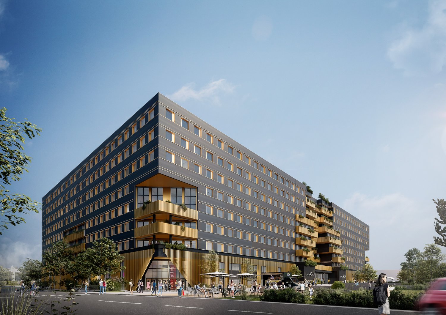 Multi-story commercial or residential building with a modern, angular design. The building has large windows, balconies, and a ground-level outdoor seating area with tables and umbrellas.