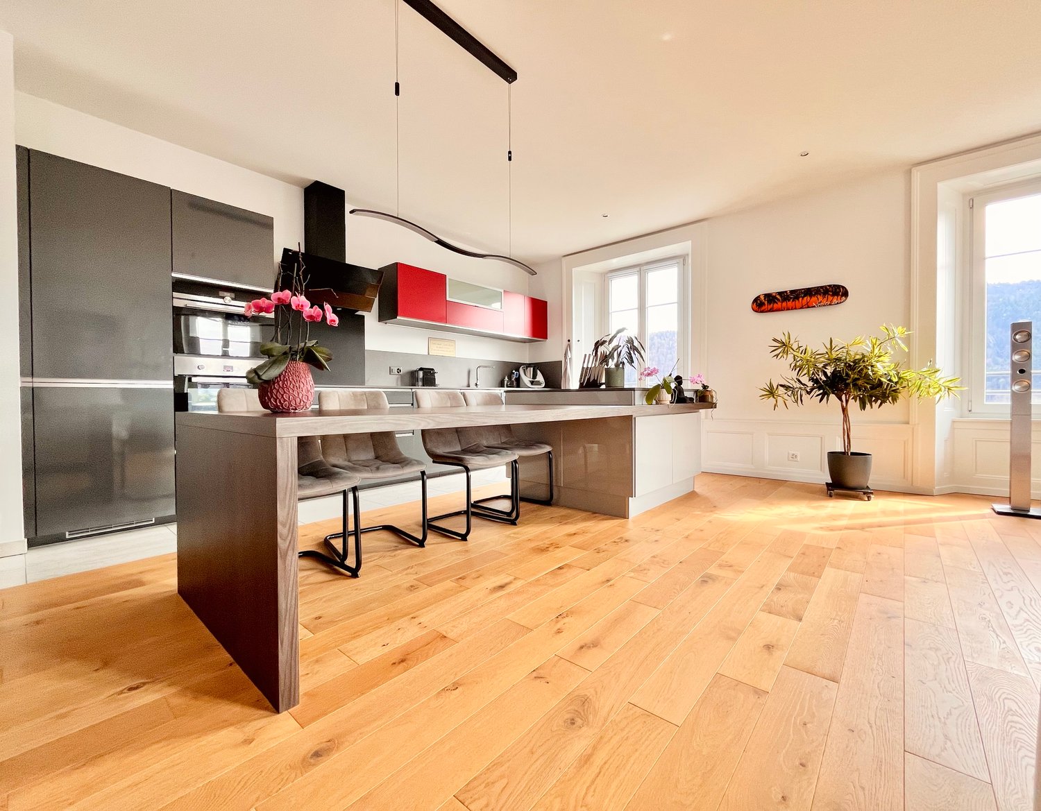 modern kitchen, large island, oak floor, stainless steel appliances, red cabinets, double oven, microwave, dishwasher, island stools