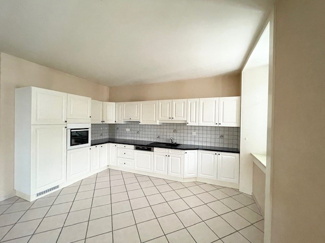 White cabinets, white countertops, black countertops, white tiled floor, built-in oven and dishwasher