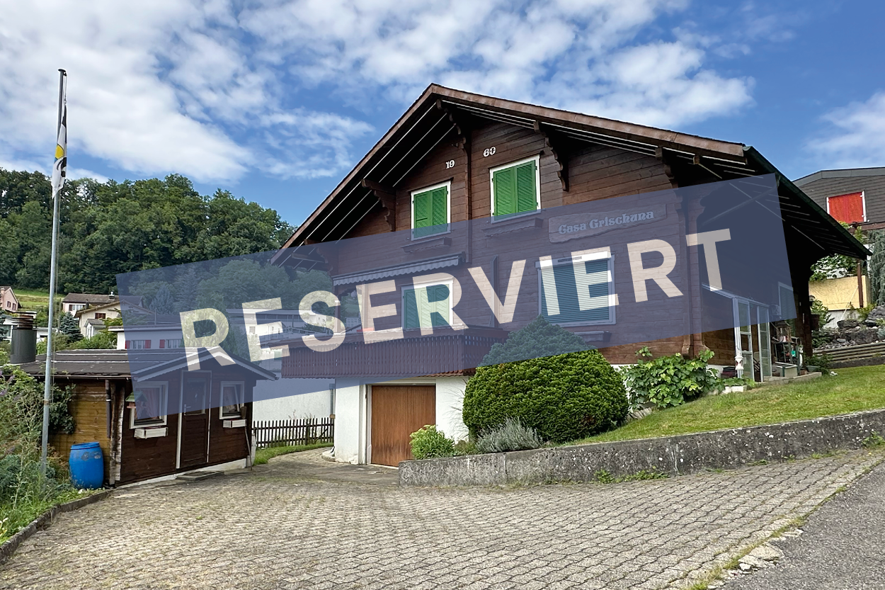 2 story wooden house, brick roof, wooden windows, wooden garage, surrounded by trees and shrubs