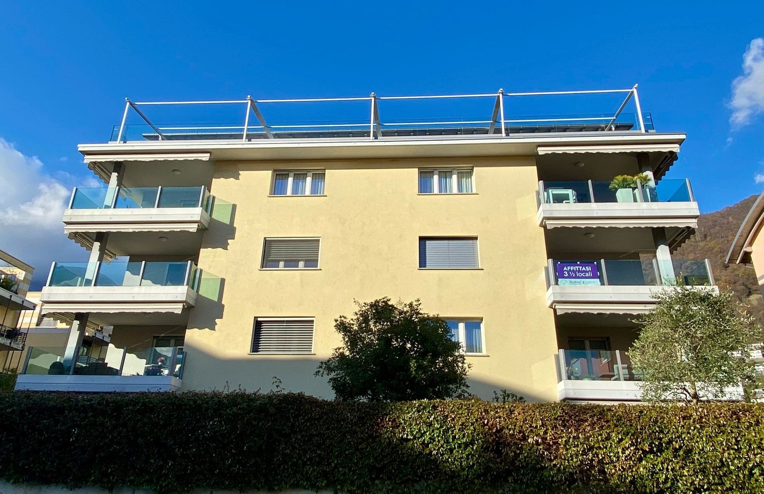 4 story building, balconies, glass railings, windows, yellow walls