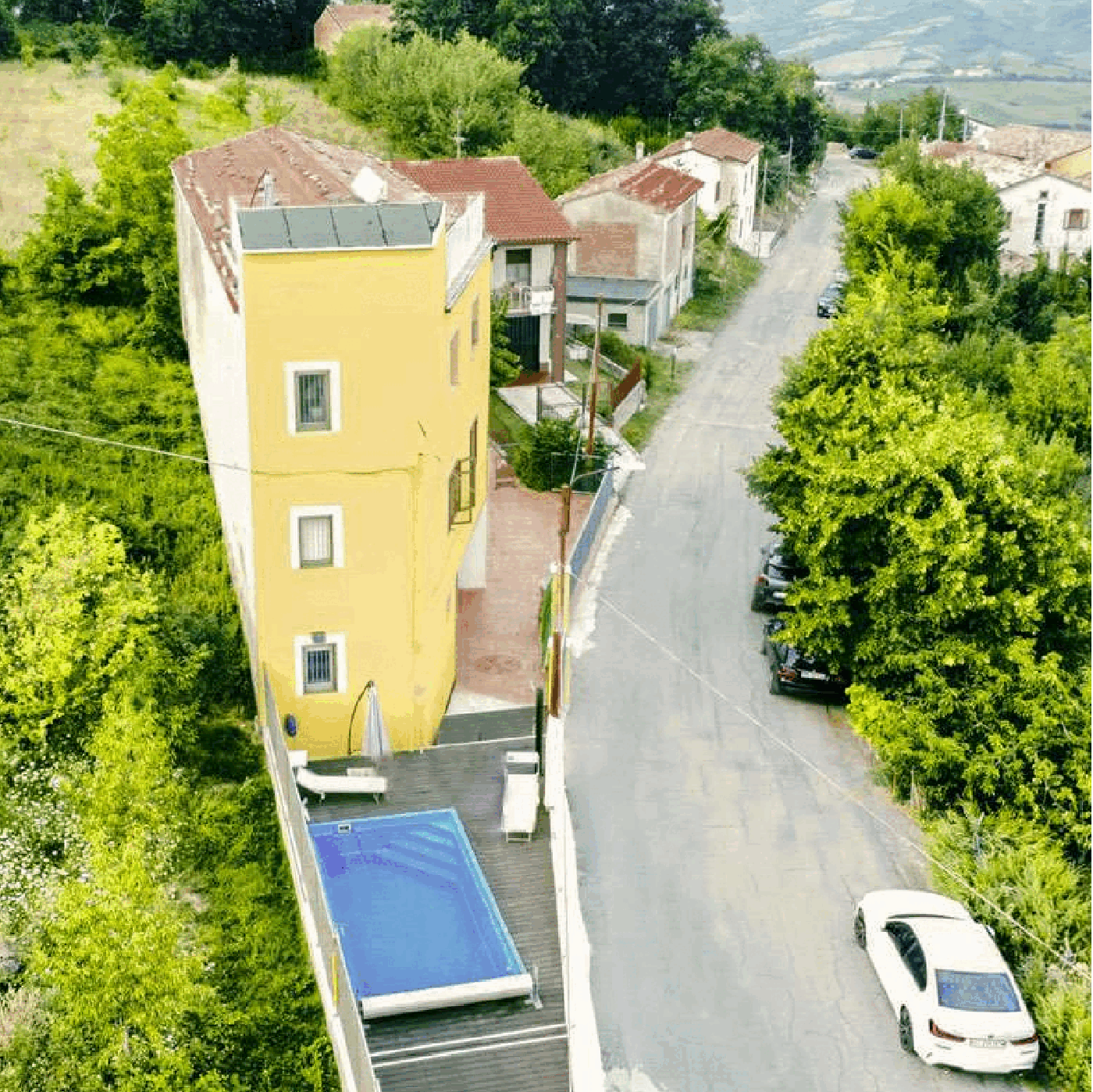 Yellow building with 4 floors, a swimming pool on the terrace and a street view