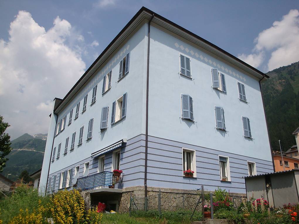 3 story white building, multiple windows, balcony, mountain view