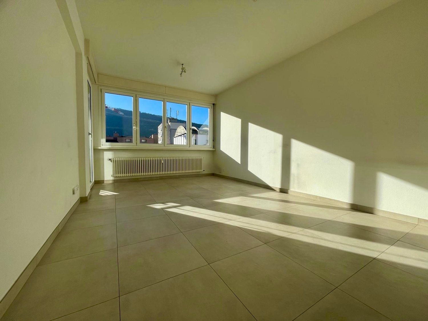 empty room, large window, tiled floor, white walls, radiator