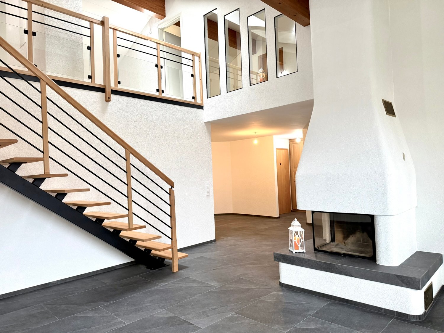 open space, fireplace, wooden stairs, glass railings, dark tiles, white walls