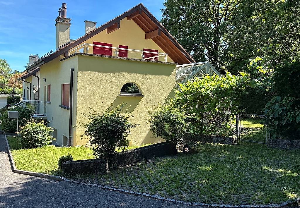 Single family house, two stories, brown roof, balcony with railing, small greenhouse, yellow walls, trees