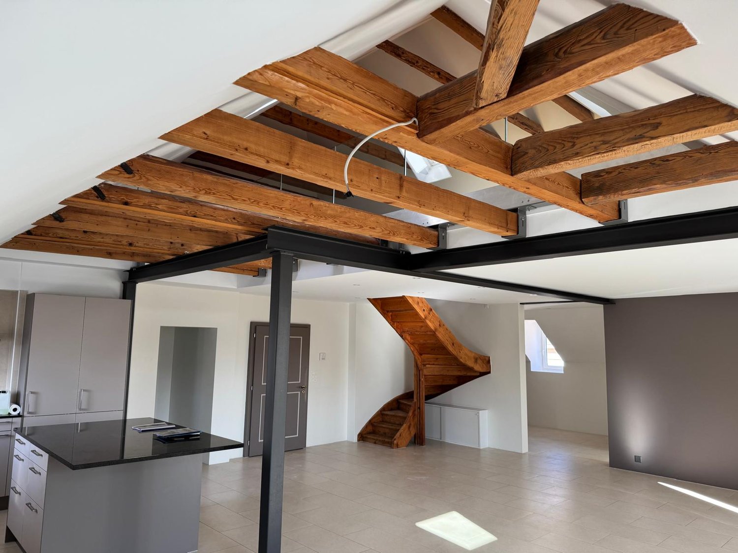 wooden beams, tiled floor, wooden staircase, gray cabinets, black countertop, windows