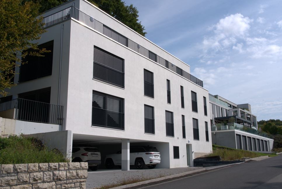 modern apartment building with 2 floors, large garage with 2 car parking spots, white exterior, black windows and shutters