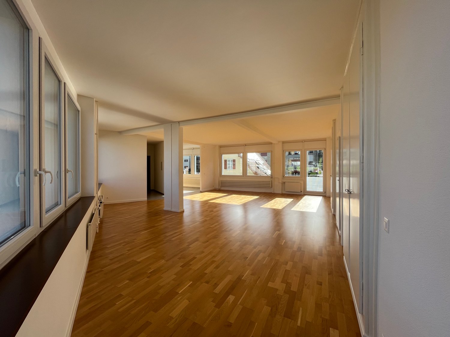 empty room, wooden floors, white walls, windows, balcony, bright