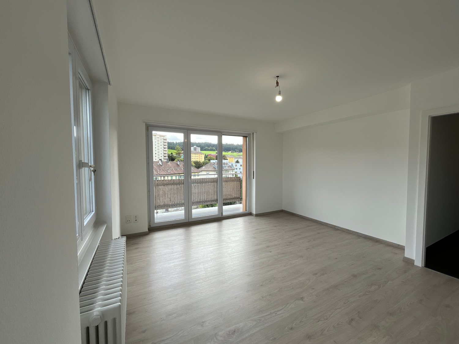 empty room with wooden floor, radiator, sliding glass door leading to balcony, no furniture