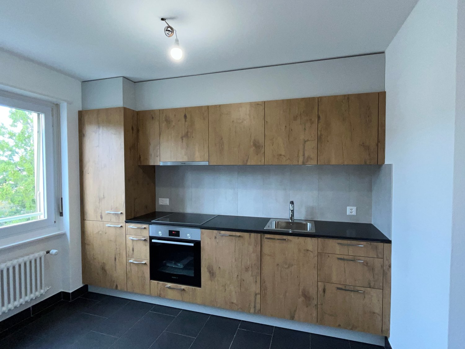 wooden cabinets, black countertop, built-in oven, stainless steel sink, light