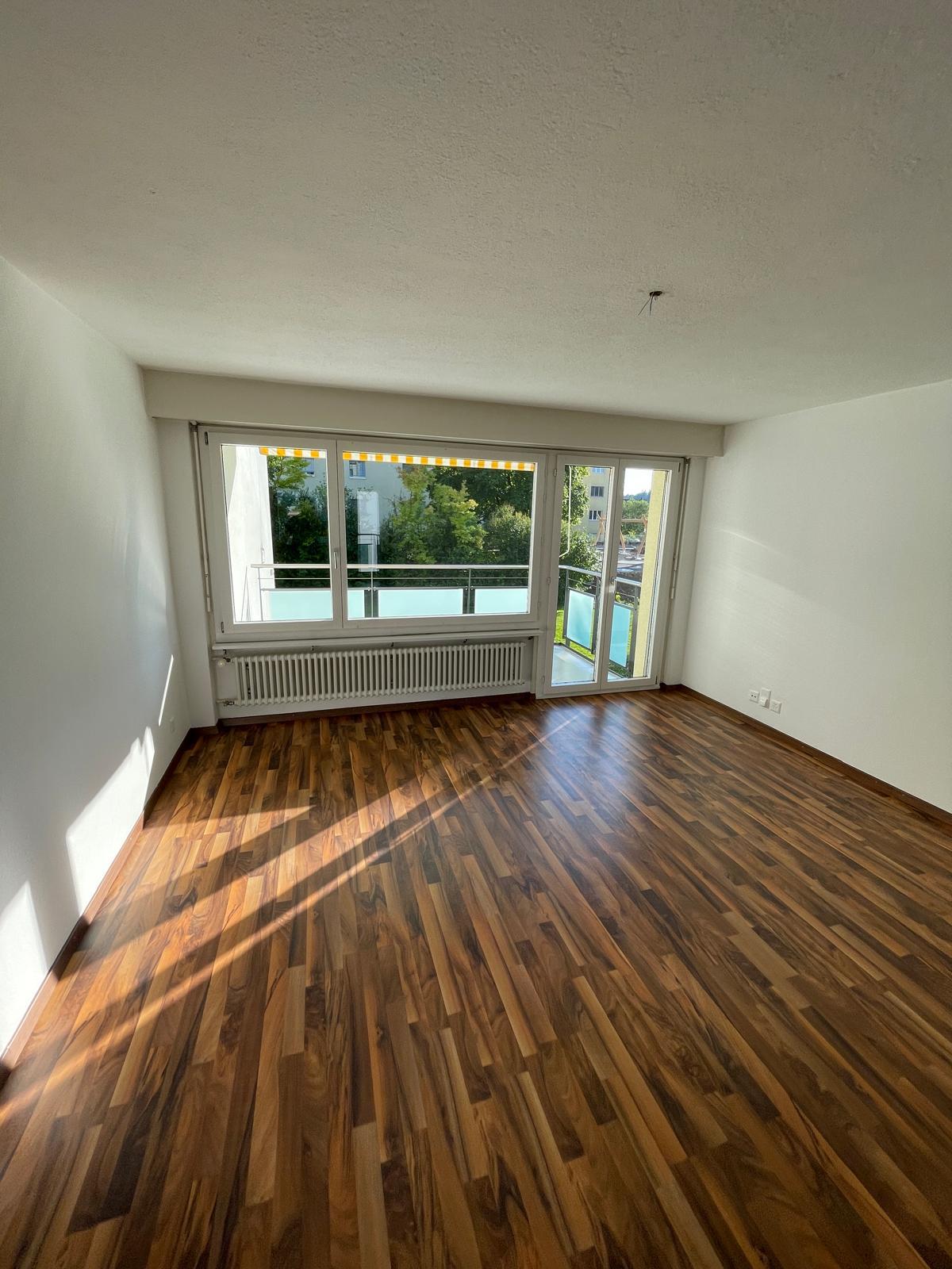 empty room, wooden floor, large sliding glass doors, balcony, white walls, white ceiling