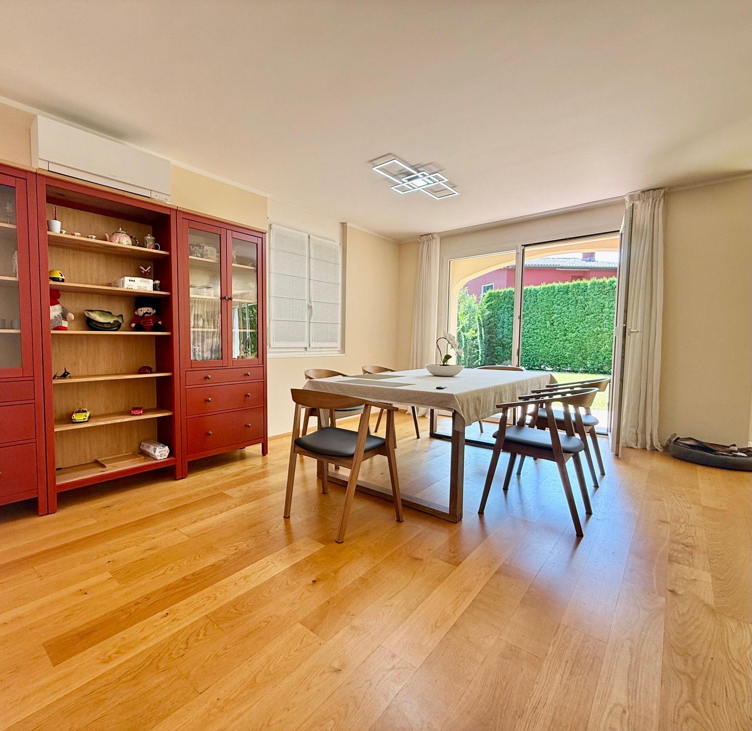 dining room with wooden floors, glass doors, table, chairs, wooden cabinet, outdoor view, air conditioner