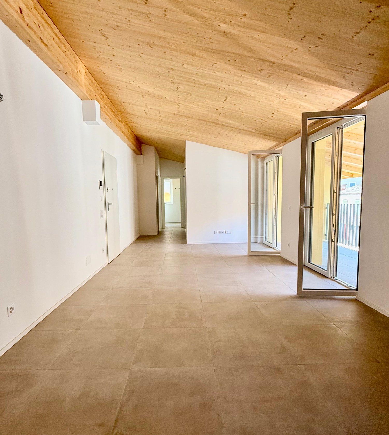Empty corridor with white walls, tiled floor, glass doors, balcony with railings