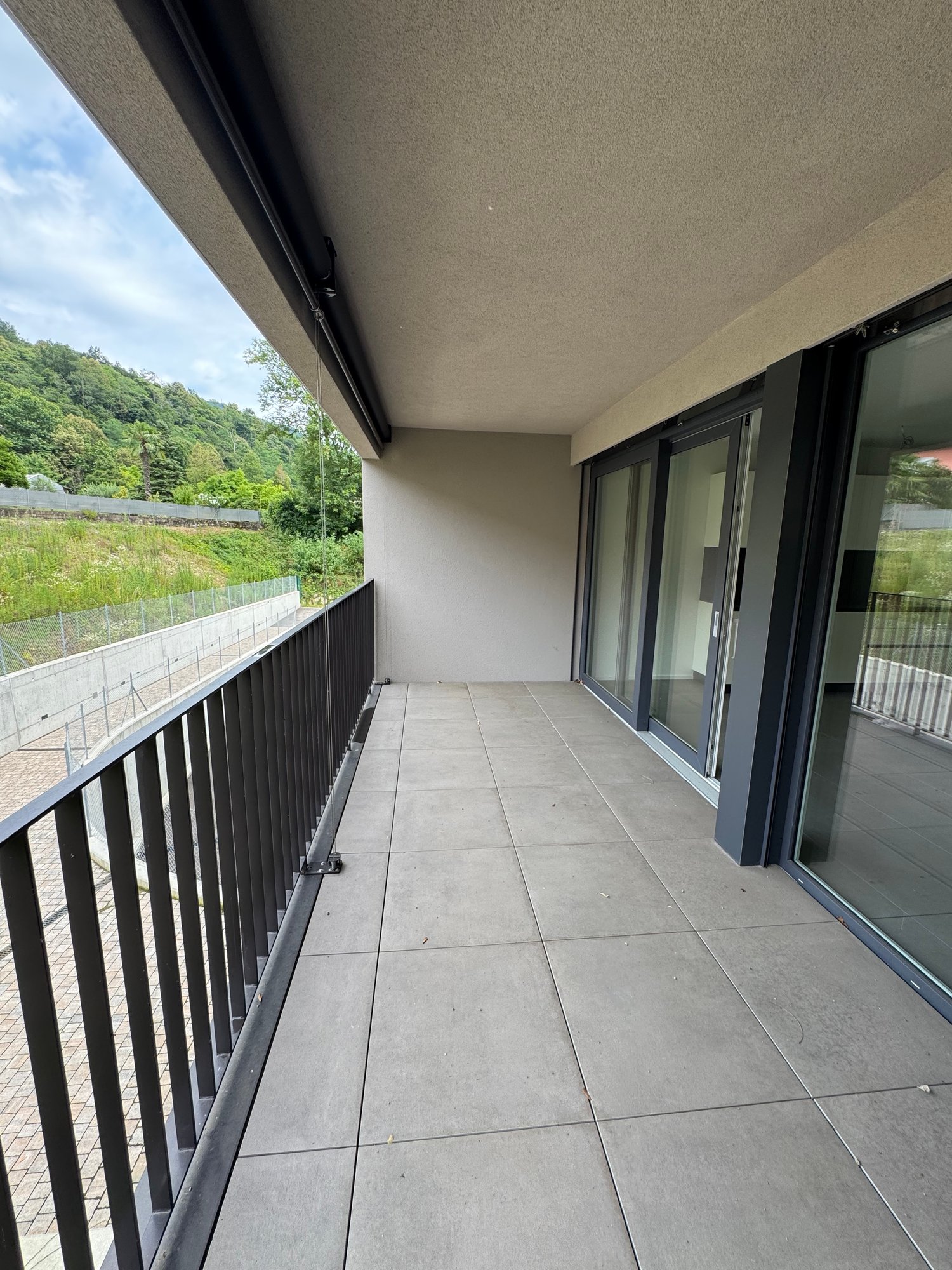 balcony with metal railings, tiled flooring, sliding glass doors, fenced outdoor area, view of greenery and hills