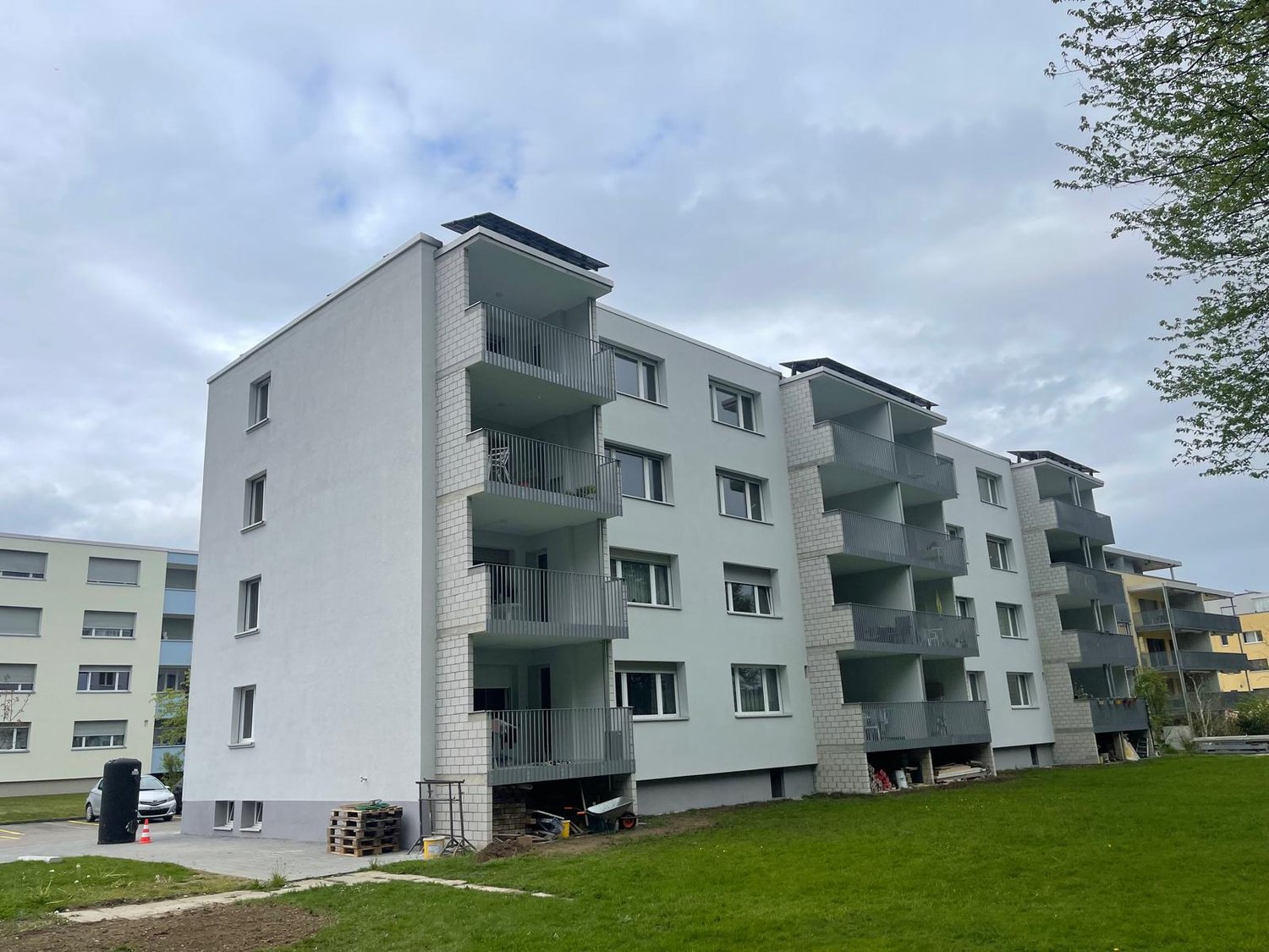 Multi-story building, balconies, windows, parking area, unfinished construction