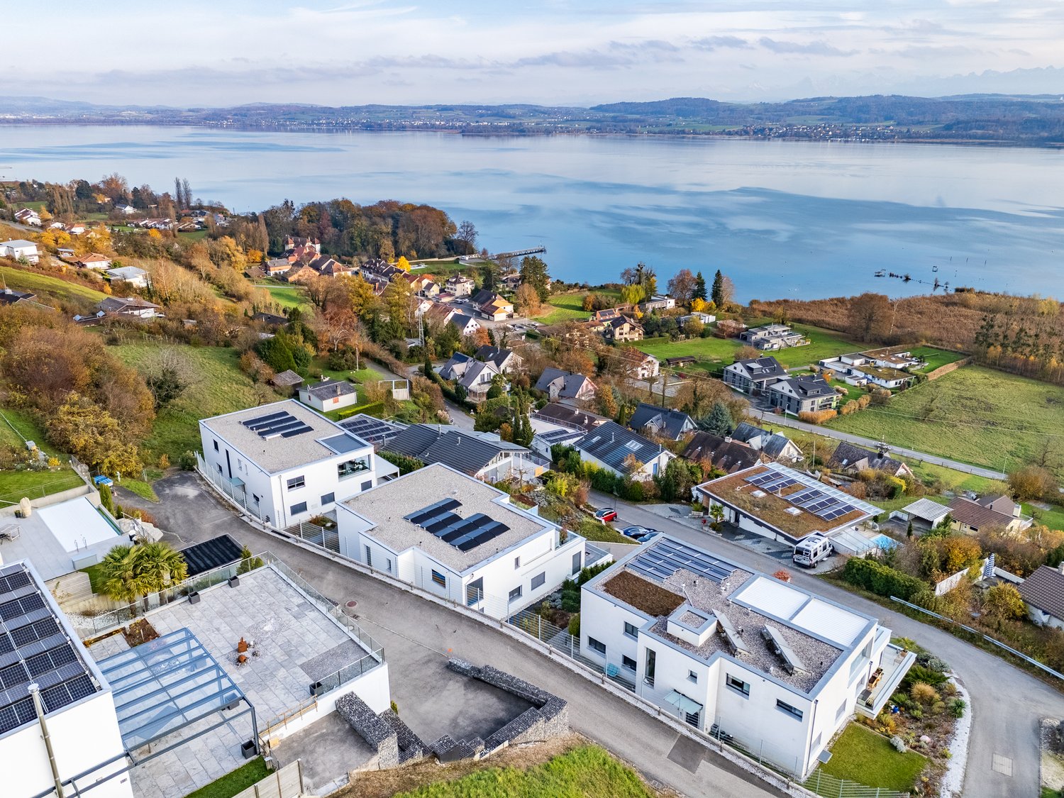 Modern houses with solar panels, view of a lake and mountains in the distance
