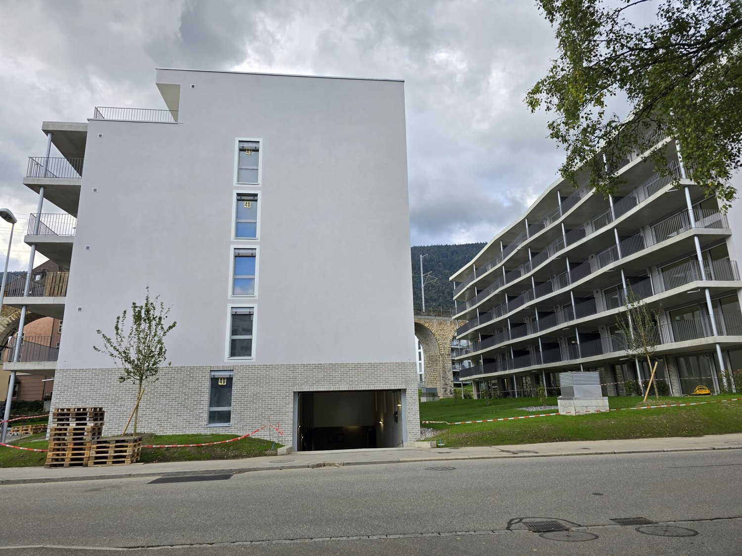 White building, balcony, garage, brick bottom part, street view
