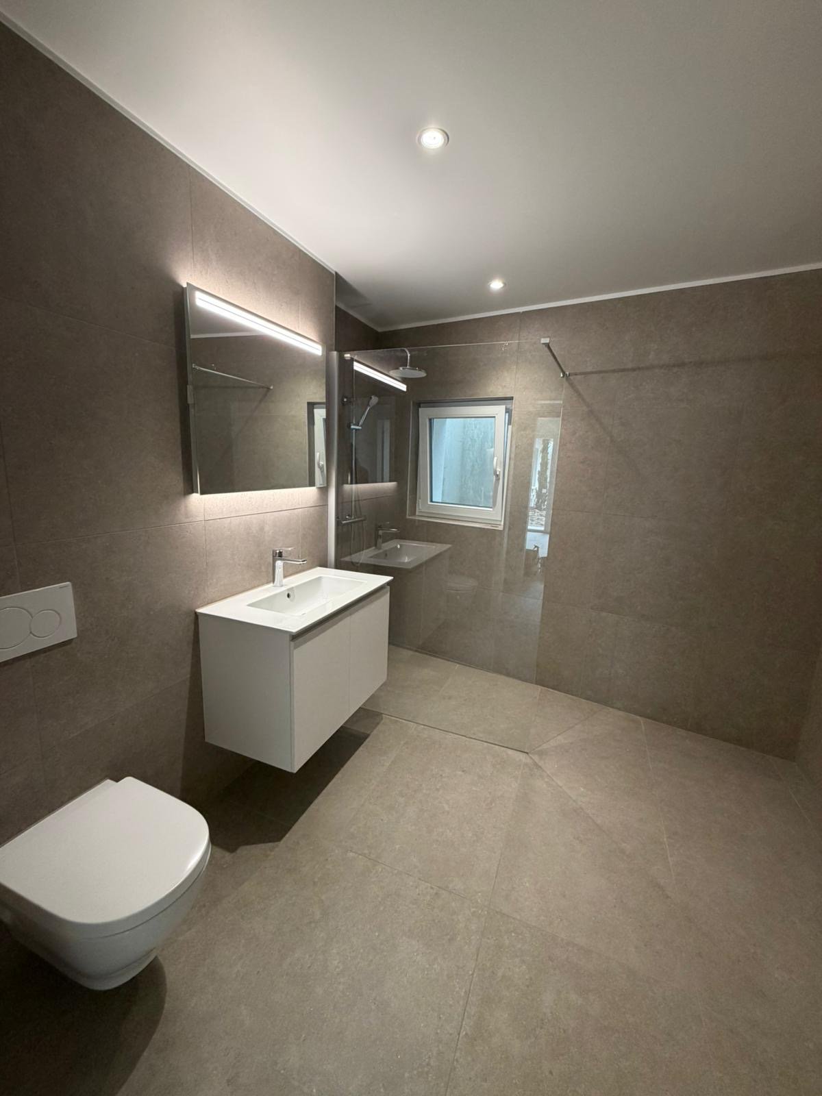 modern bathroom with white sink, mirror, toilet, and glass shower enclosure