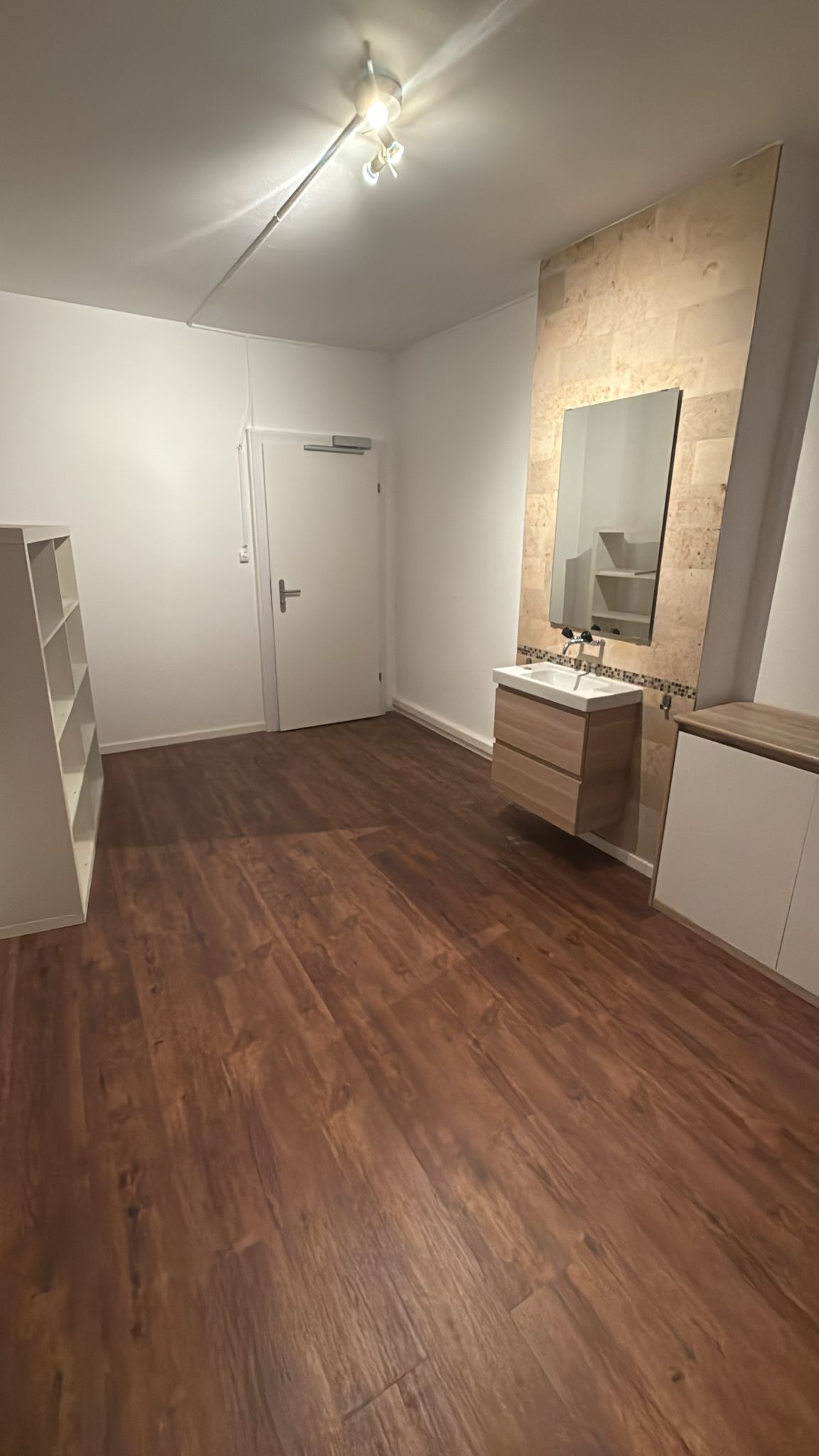 empty room, wooden floors, white walls, ceiling lamp, mirror, sink, cabinets