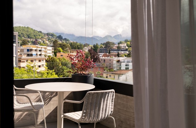 outdoor balcony with table and chairs, glass railing, potted plant, city view, mountain view