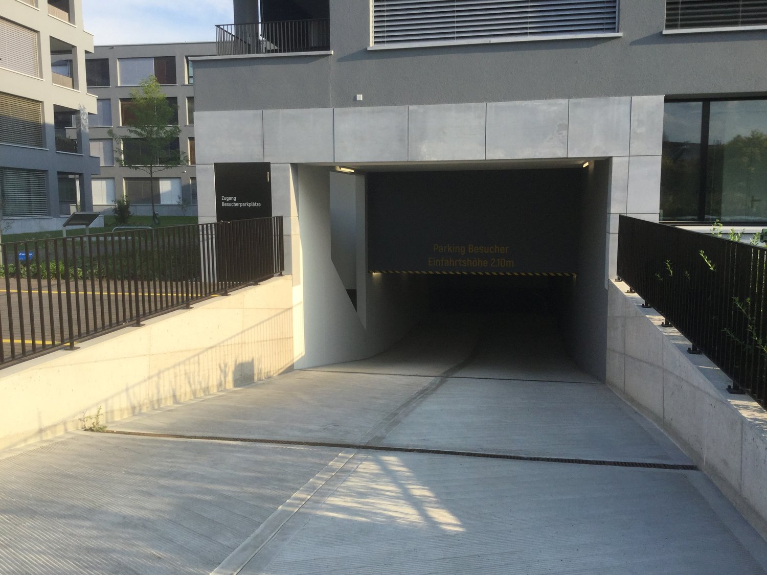 Parking lot for guests, entrance to the building, concrete walls, underground parking, iron railings, sign indicating the height restriction