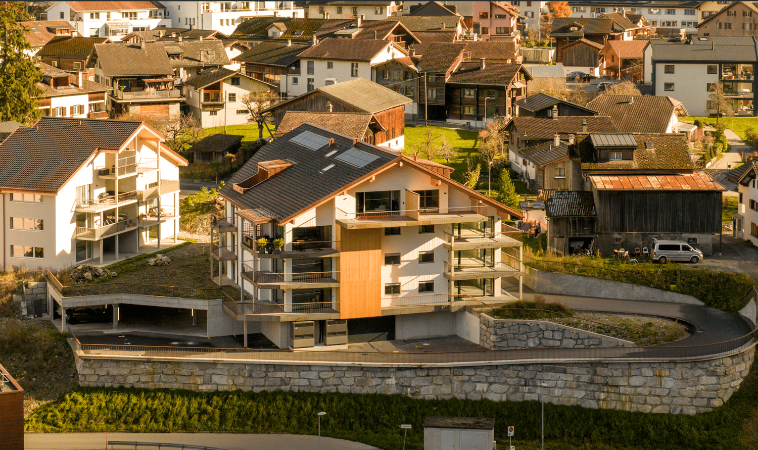 Modern house with multiple floors, solar panels on the roof, balconies, garage, green roof, stone wall