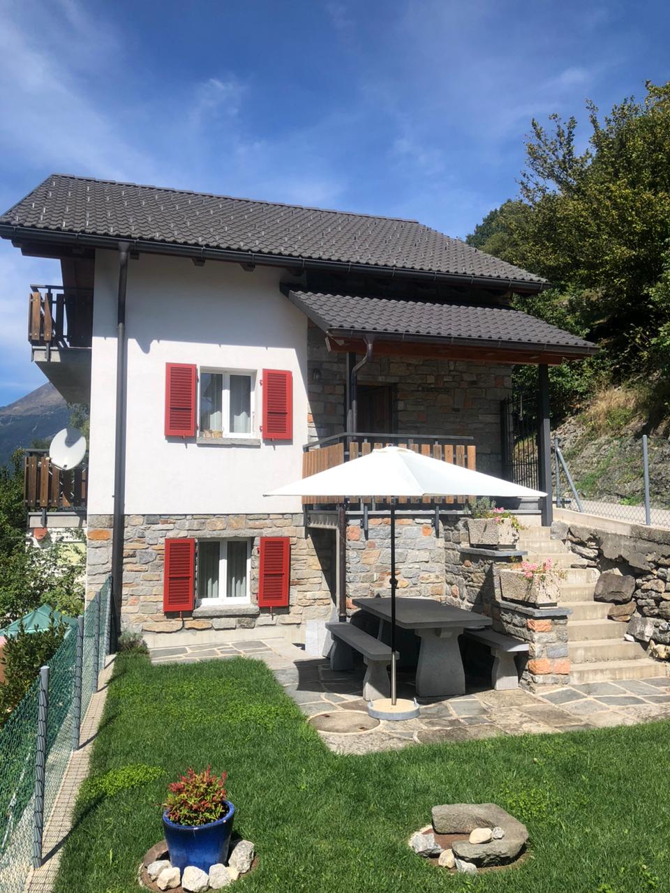 2 story house, white and red shutters, stone wall, balcony, garden, table and bench, satellite dish