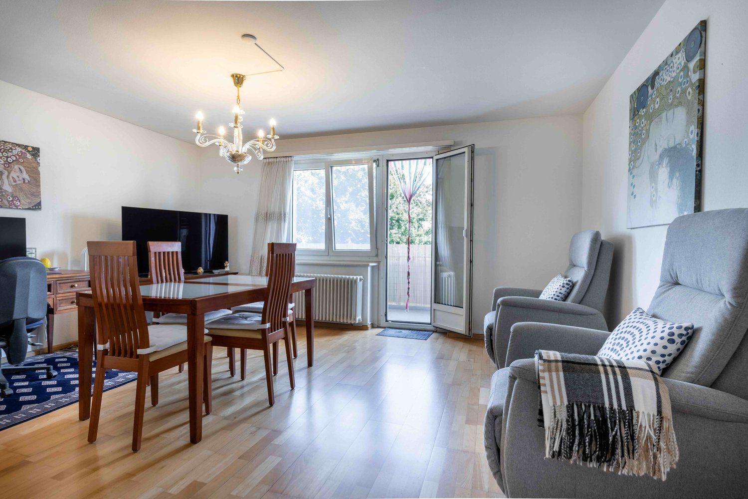 dining room with a table and chairs, a television, a chandelier, and a balcony