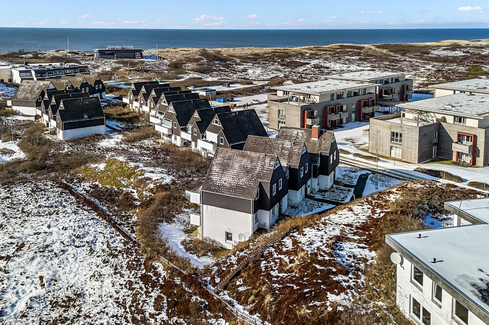 Aerial view of a row of houses with snow on the ground, near the sea