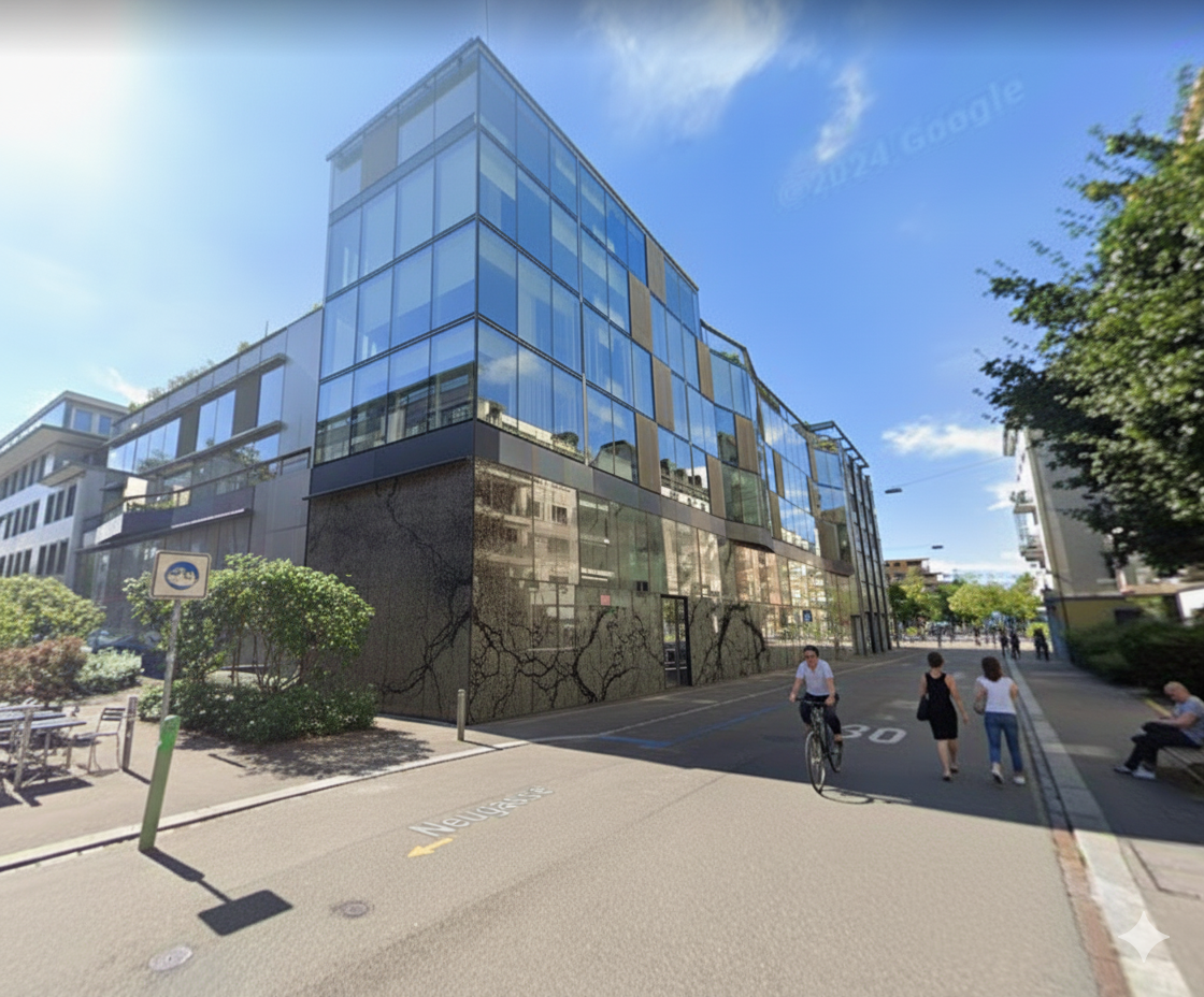 Modern building with glass facade, multiple floors, located on a street with people walking and a cyclist
