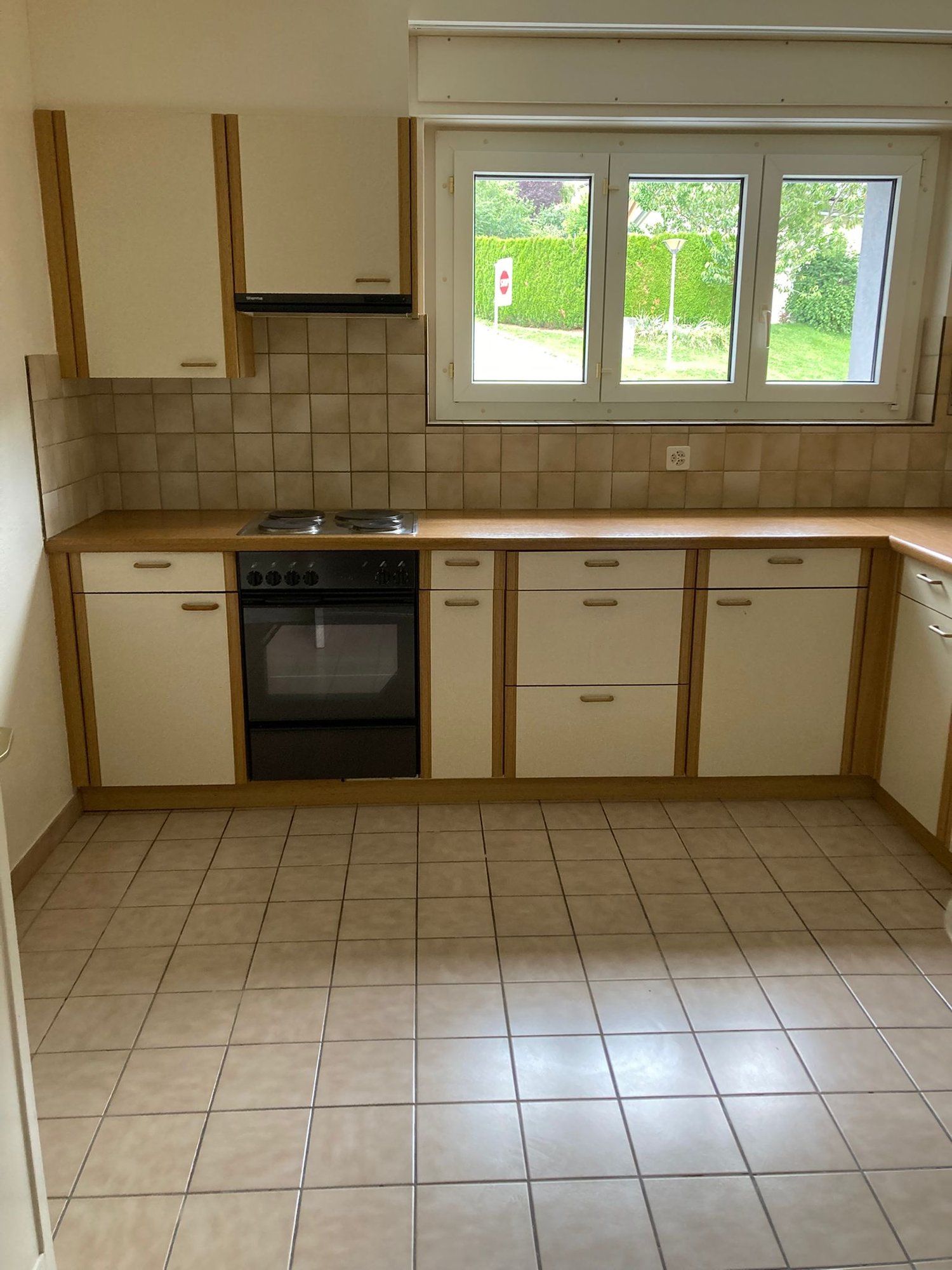 A modern kitchen with tiled flooring, white cabinets, wooden countertops, and a gas stove with an oven below.