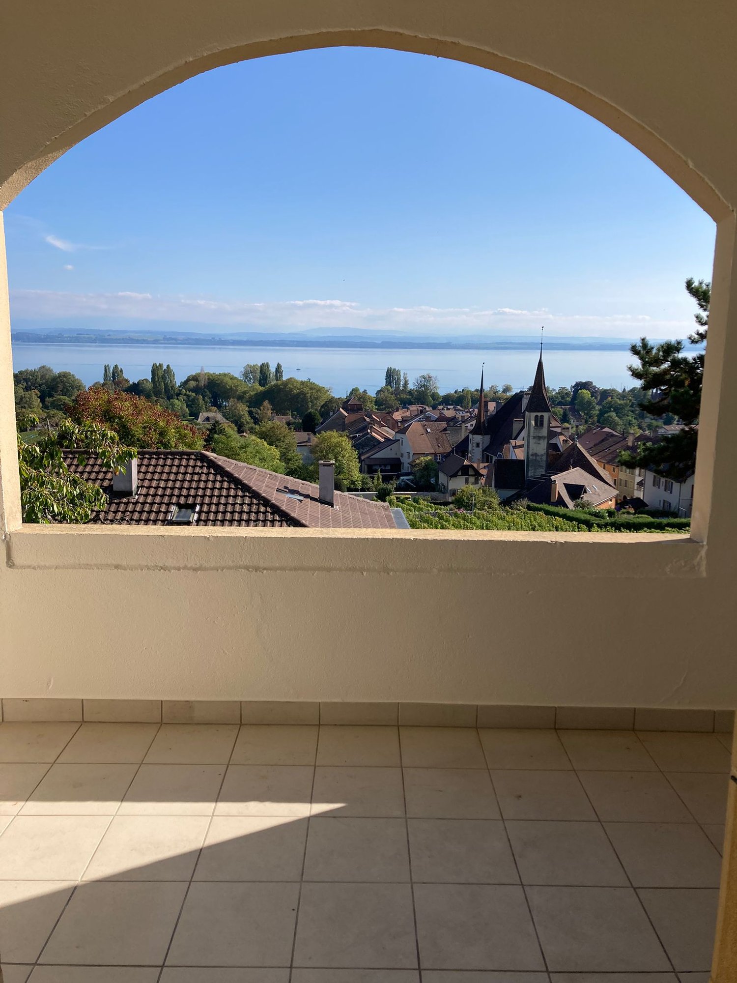 Arch shaped window with view to the lake, village and houses.