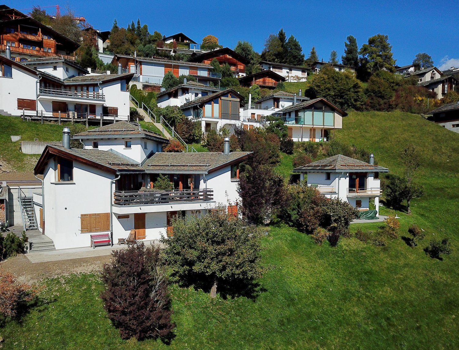 Aerial view of a hillside residential neighborhood with several houses with balconies and staircases.