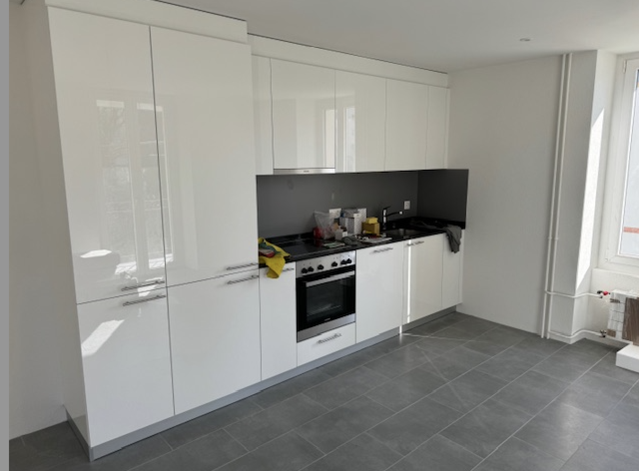 Modern, white kitchen cabinets, black countertop, stove, dishwasher, tiled floor