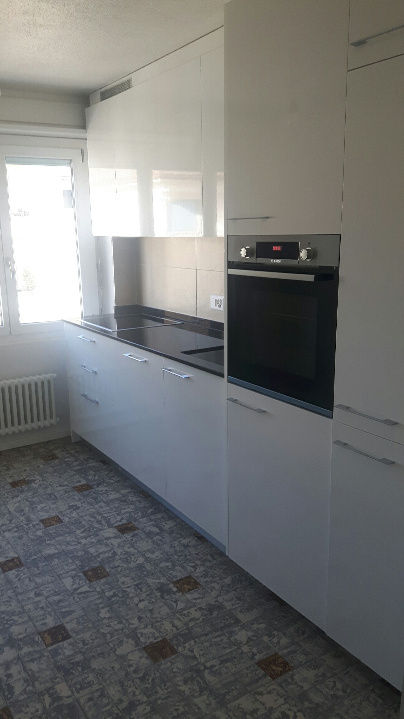 Modern kitchen with white cabinets, black oven, and tile flooring