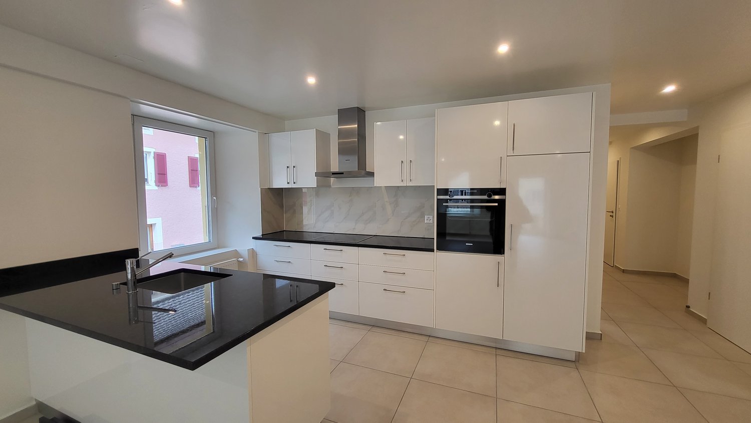 kitchen with a sink, countertop, gas stove, oven, and fridge. Cabinets and drawers underneath.